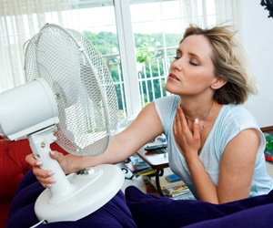 Woman using an electric fan to cool off.