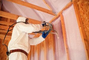 Worker installing spray foam insulation.