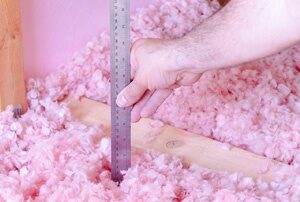 Worker measuring the depth of installed insulation.