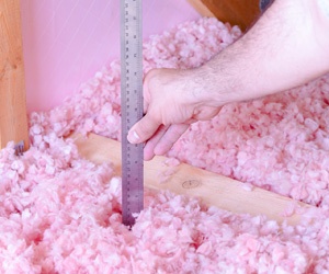 Worker measuring the depth of installed insulation.
