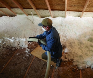 Worker installing insulation in an attic.