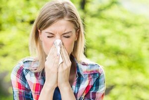 Woman outside experiencing allergy symptoms.