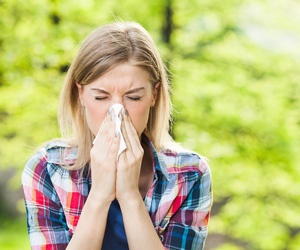 Woman outside experiencing allergy symptoms.