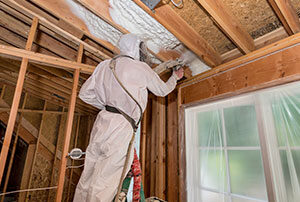 Worker installing spray foam in a ceiling.