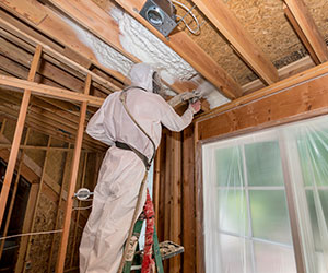 Worker installing spray foam in a ceiling.