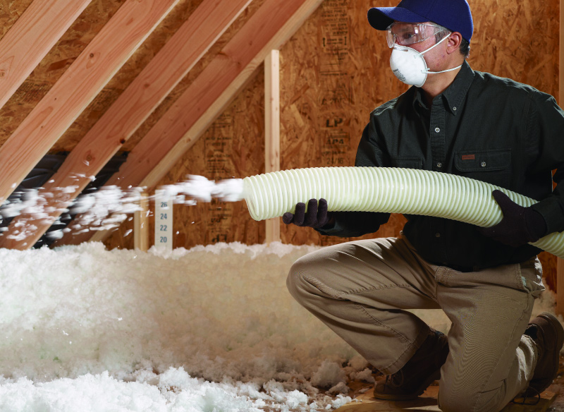 Insulation installer insulating attic with blown-in insulation.