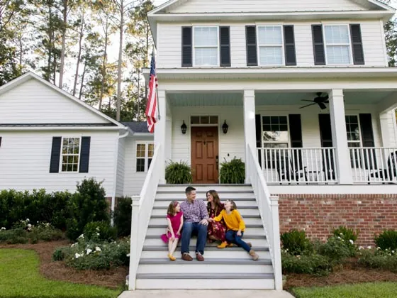 Happy family sitting together on front steps of home