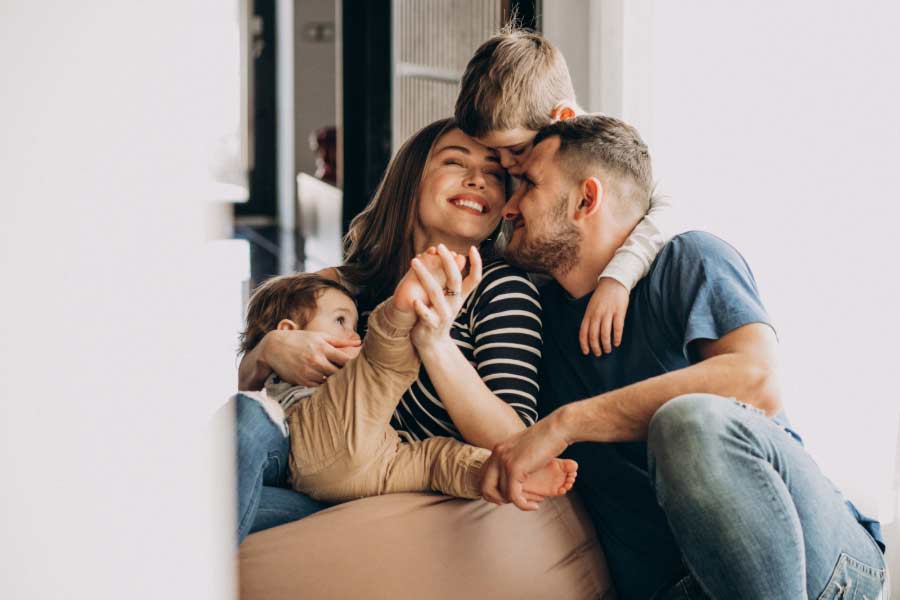 Happy family of four, hugging at home.