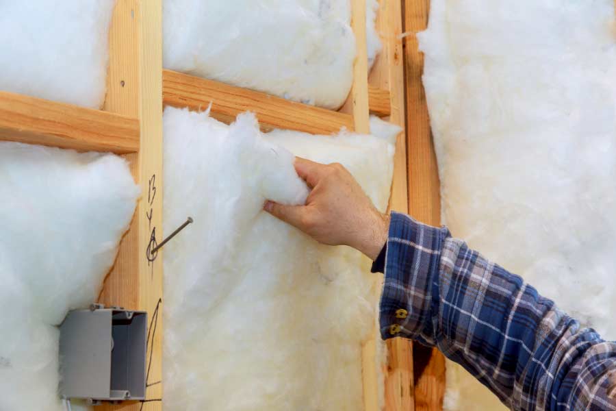 Fiberglass insulation installer, insulating home's walls.