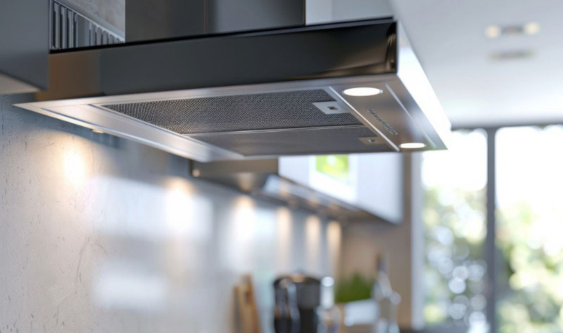 Steel kitchen exhaust fan, in home's kitchen, with a blurred background.