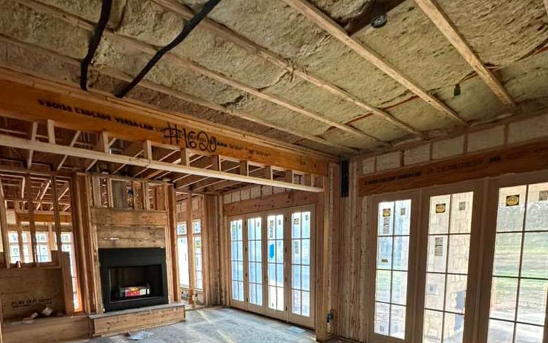 Residential living room framing stage with mineral wool insulation, in new home build.