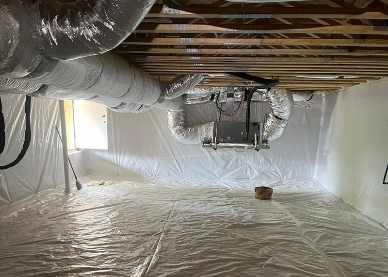 Insulated crawl space with silver ductwork and wooden beams, bright light from an open door on the left