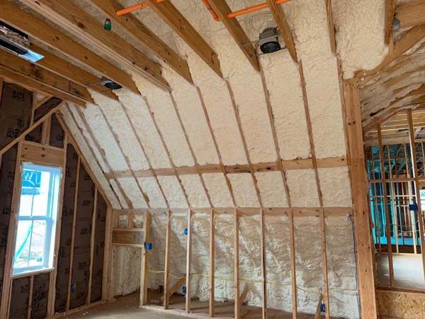 Spray foam insulation applied between wooden studs in an unfinished attic wall