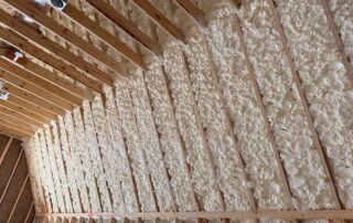 Partially completed spray foam insulation installation on sloped roof rafters. Partially completed spray foam insulation installation on sloped roof rafters with electrical boxes in a Nashville new construction home.