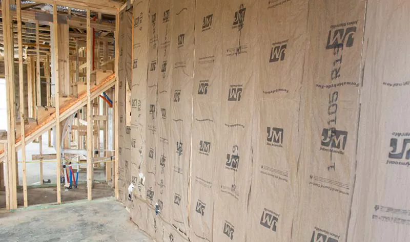 Johns Manville kraft-faced fiberglass batt insulation installed in framed exterior wall cavities of a new construction home.