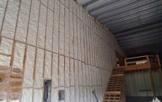 Open-cell spray foam insulation on walls beside a wood-framed staircase. Open-cell spray foam insulation on walls beside a wood-framed staircase.