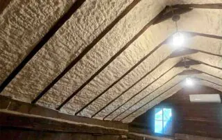 Open-cell spray foam insulation on rafters of historic log cabin attic at Belle Meade Plantation, Nashville, TN — Hayes Insulation Nashville, Hood Company restoration.