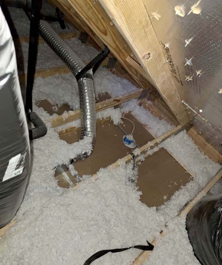 Blown-in fiberglass insulation installed around HVAC flex ductwork in attic floor during repair, Nashville, TN.