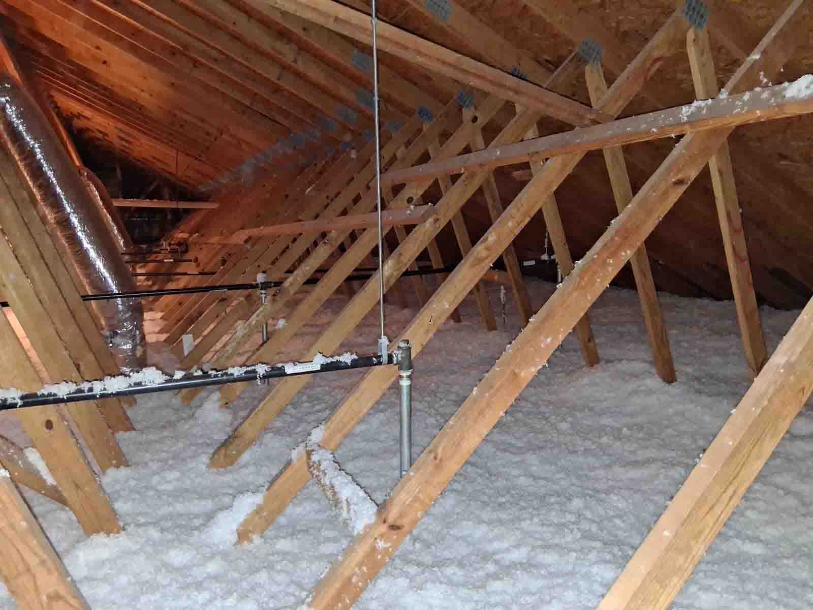 Blown-in fiberglass insulation covering attic floor with exposed rafters and ductwork, Nashville, TN.