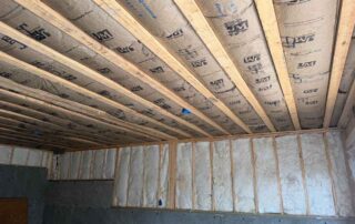 Kraft-faced fiberglass batt insulation between basement ceiling joists and unfaced batts in framed walls above the concrete foundation.