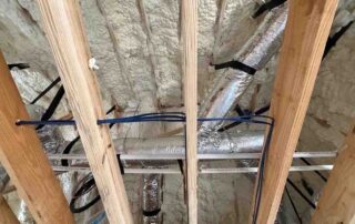 Fiberglass batts in one wall meeting open-cell spray foam in a new AJSF Heritage Homes build.