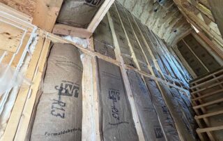 Fiberglass batt insulation along a tall stairwell wall, with open-cell spray foam on the roof deck above, in a new AJSF Heritage Homes build, Nashville, TN, by Hayes Insulation Nashville