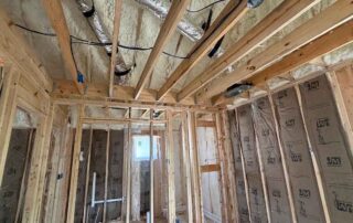Open-cell spray foam insulation on the roof deck above open ceiling joists and framed bedroom walls with kraft-faced fiberglass batts, new AJSF Heritage Homes construction, Nashville, TN, by Hayes Insulation Nashville.